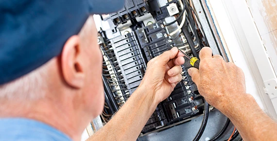 Close-up of hands repairing a circuit breaker, highlighting circuit breaker replacement and repair services in Bowie MD.
