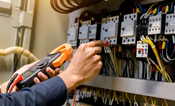 Electrician using multimeter to test electrical panel during maintenance in Silver Spring, MD.