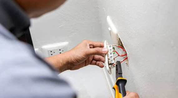 Technician repairing electrical outlet for reliable service in Frederick, MD.